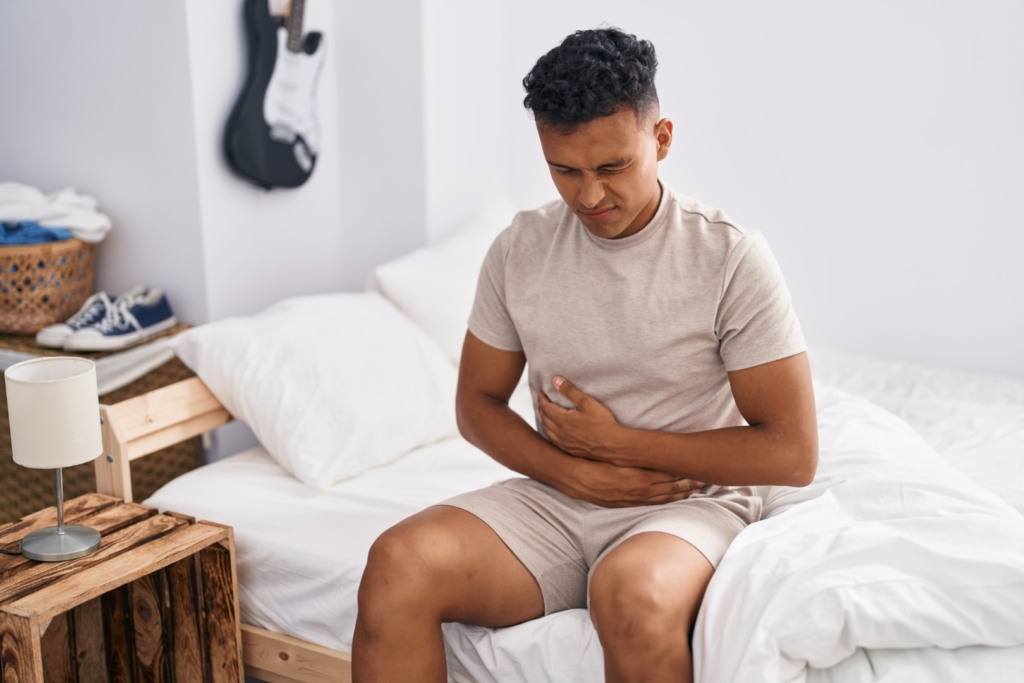 Young latin man suffering for stomach flu at bedroom
