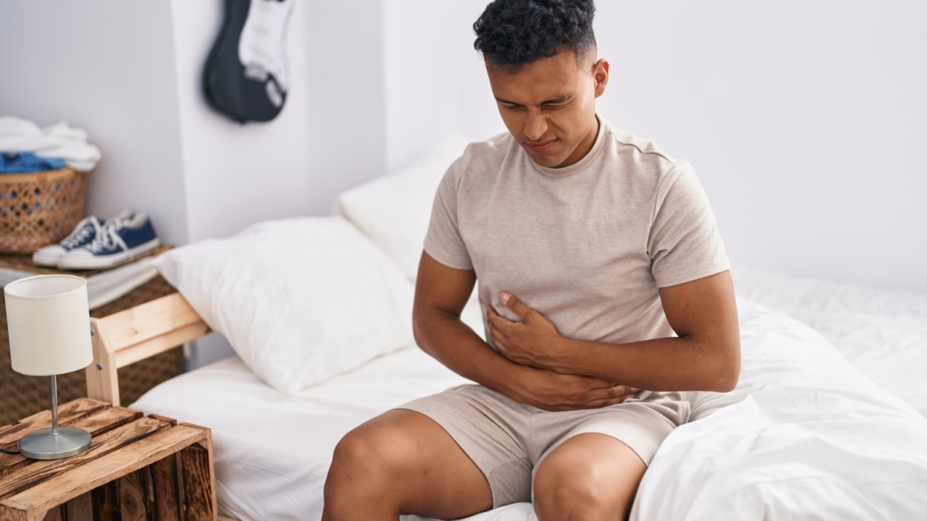 Young latin man suffering for stomach flu at bedroom