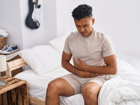Young latin man suffering for stomach flu at bedroom