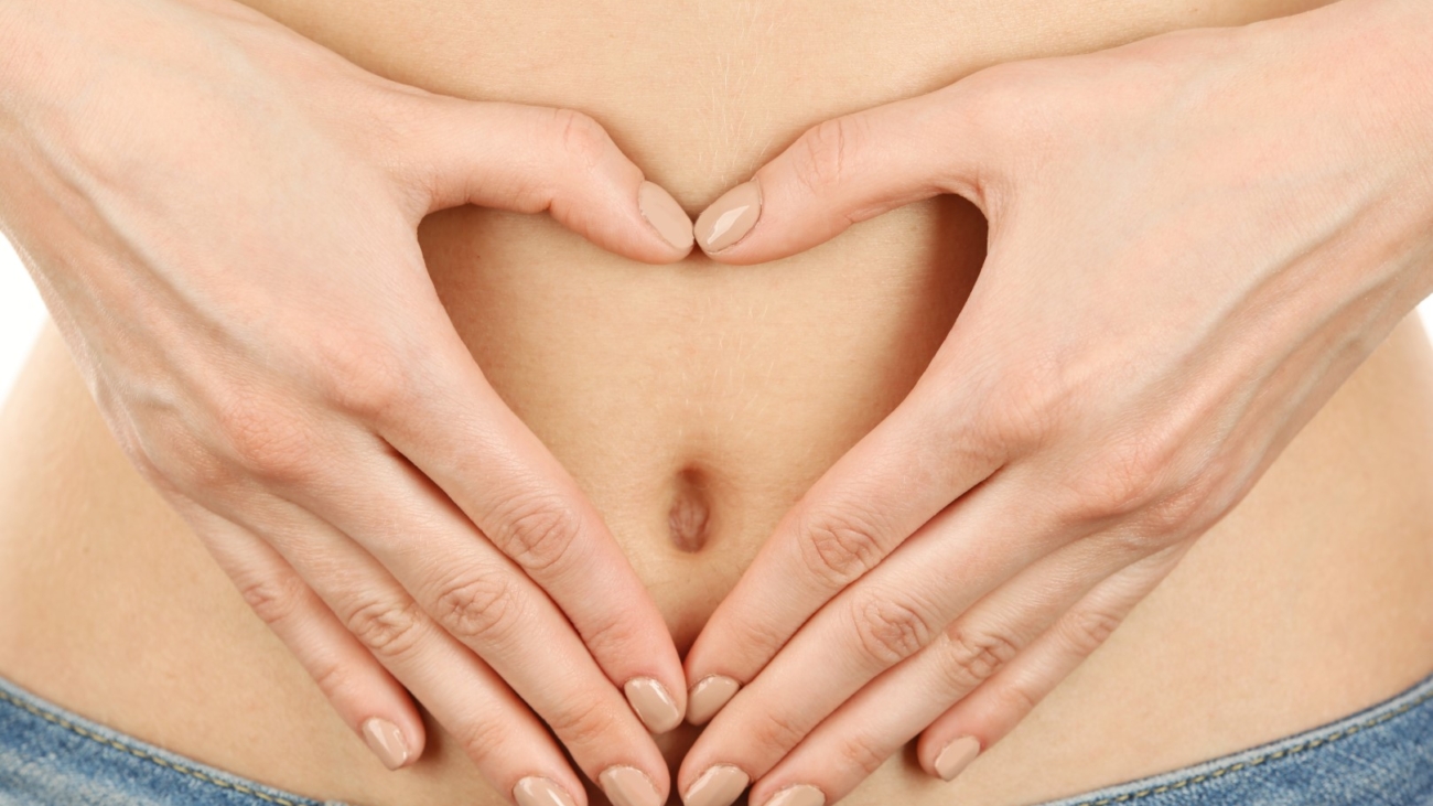 Hands forming heart on female belly button. Healthy stomach health concept, or early pregnancy concept