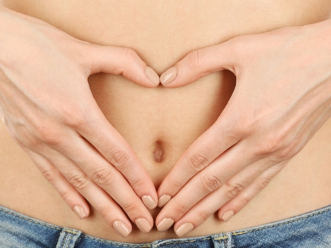 Hands forming heart on female belly button. Healthy stomach health concept, or early pregnancy concept