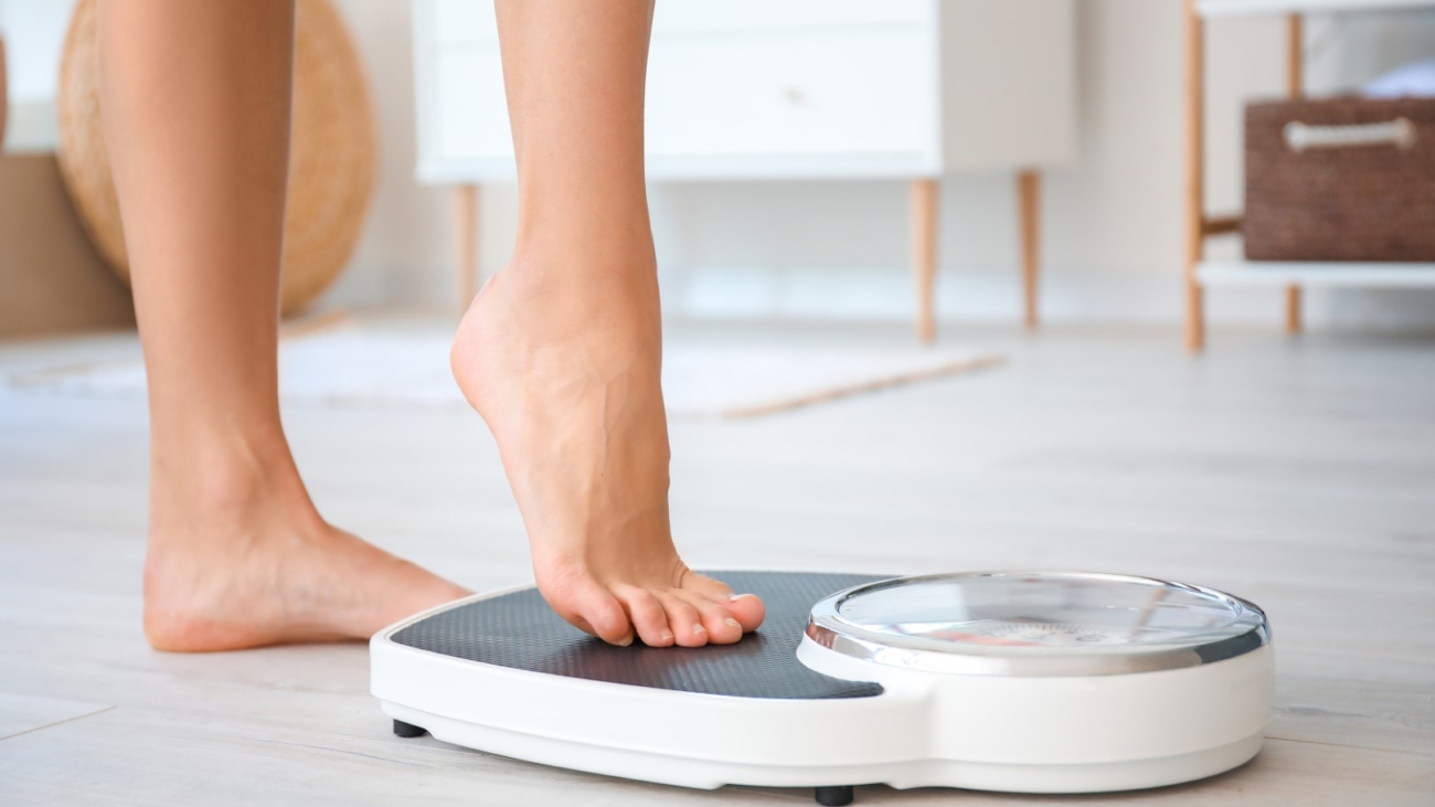 Young woman measuring her weight at home