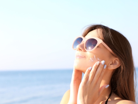 Young woman using sunscreen on the sea background