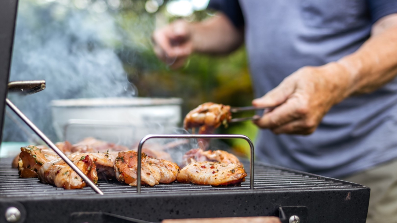 Senior man preparing barbecue grill for garden party. Selective